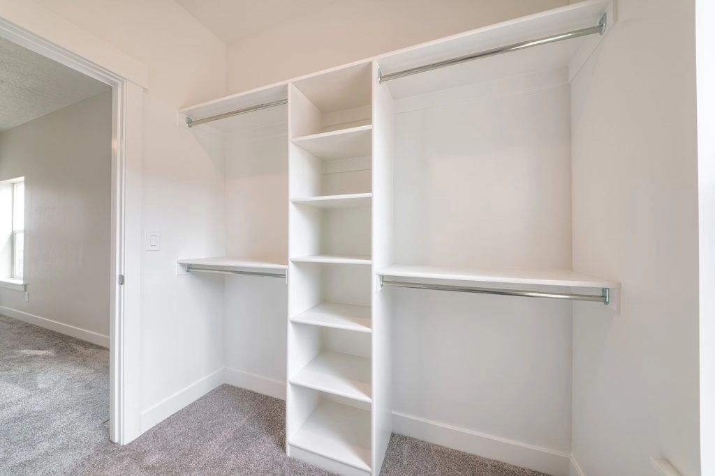 Spacious white shelving unit with hanging rods in a clean, organized closet, perfect for holiday preparations.
