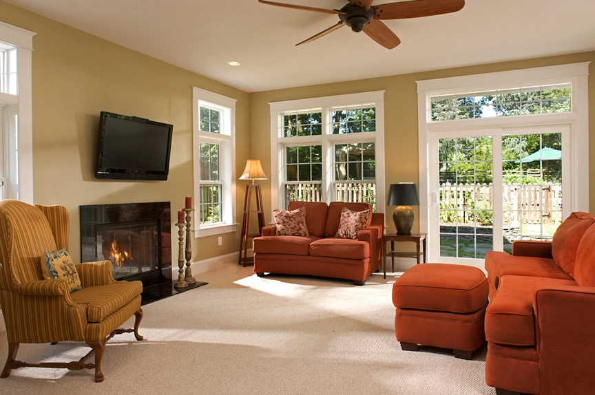 Cozy living room featuring orange sofas, a fireplace, and large windows with natural light, ideal for home remodeling.
