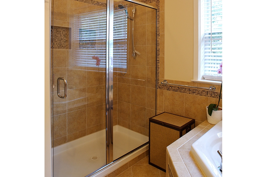 Modern glass shower enclosure with beige tile and decorative accents in a stylish bathroom setting.