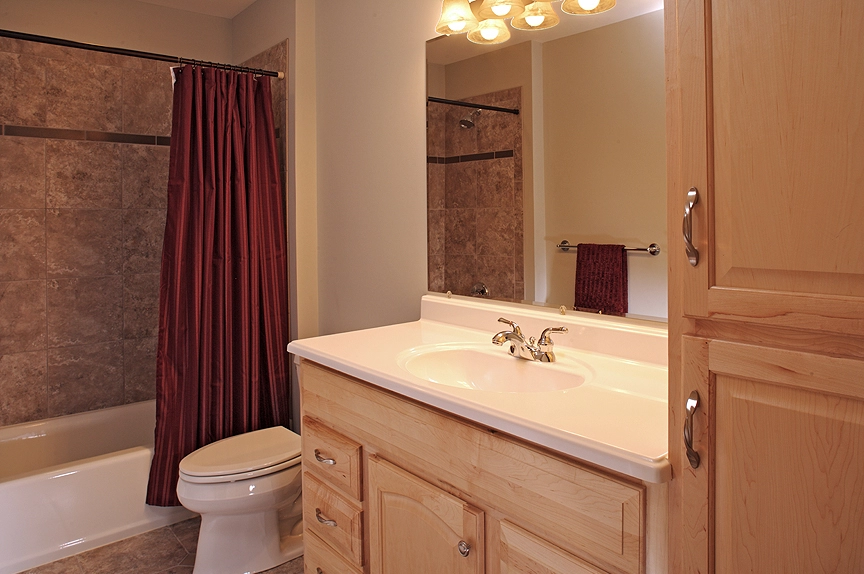 Elegant bathroom featuring a wooden vanity, white sink, and burgundy shower curtain, perfect for remodeling ideas.