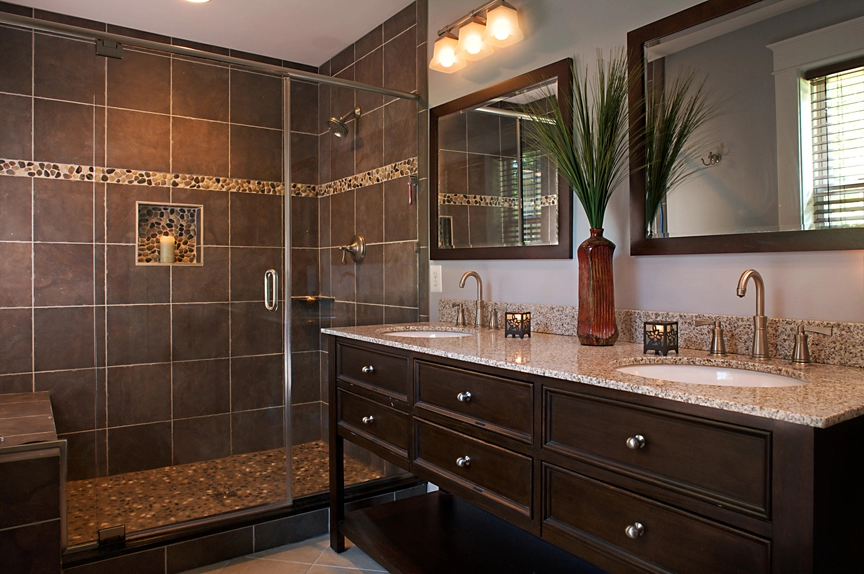 Modern bathroom featuring a spacious walk-in shower with tile accents and dual sink vanity in dark wood.