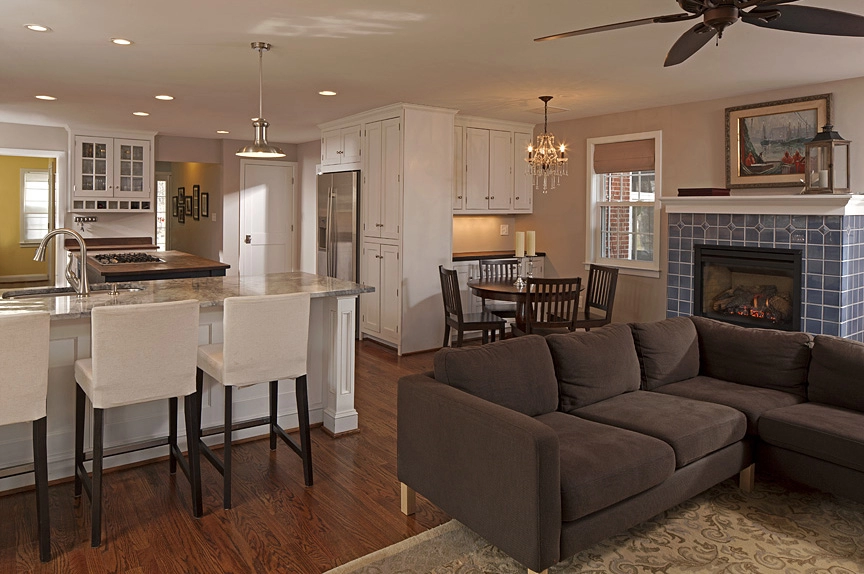 Modern kitchen with white cabinetry, granite countertops, and a cozy dining area featuring dark wood furniture.