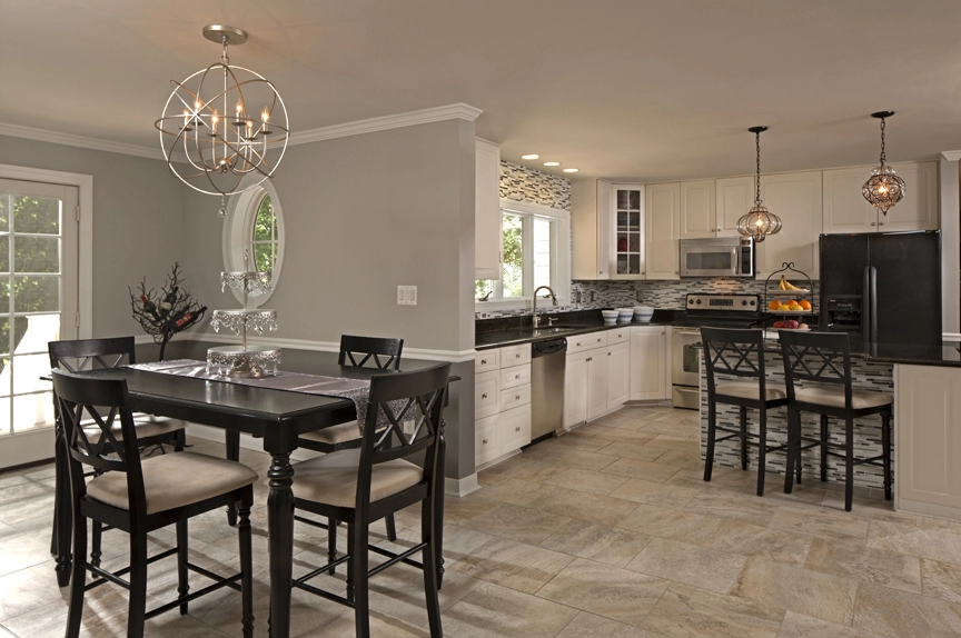Modern kitchen featuring white cabinetry, stone countertops, and a stylish dining table with black chairs.