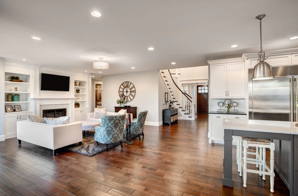 Spacious living room featuring hardwood flooring, modern furniture, and a stylish staircase.