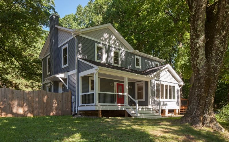 Charming two-story house with gray siding, white trim, red door, and a spacious deck in Catonsville.