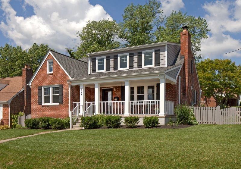 Charming brick house with a front porch, landscaped yard, and modern roof, showcasing quality construction.