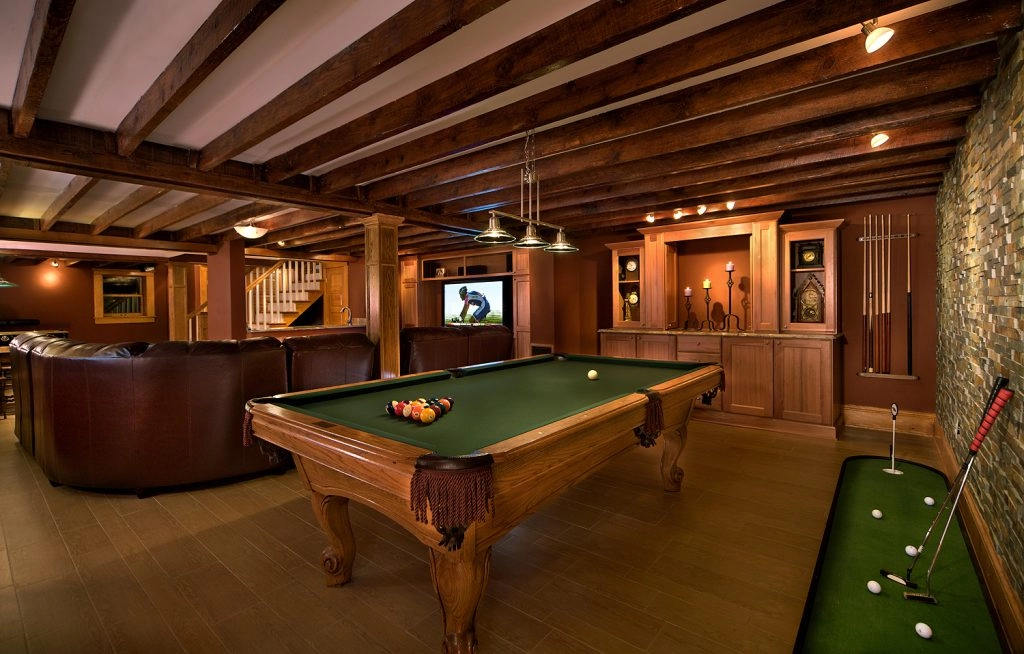 Stylish basement game room featuring a green pool table, leather seating, and a flat-screen TV.